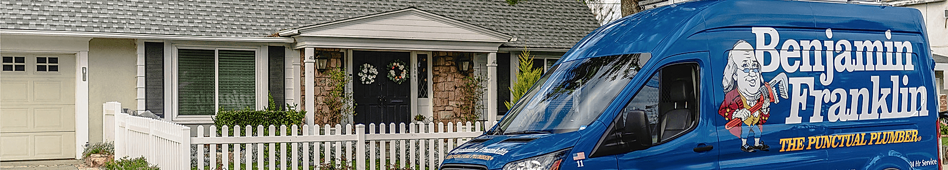 Benjamin Franklin Plumbing service van parked in front of a house.